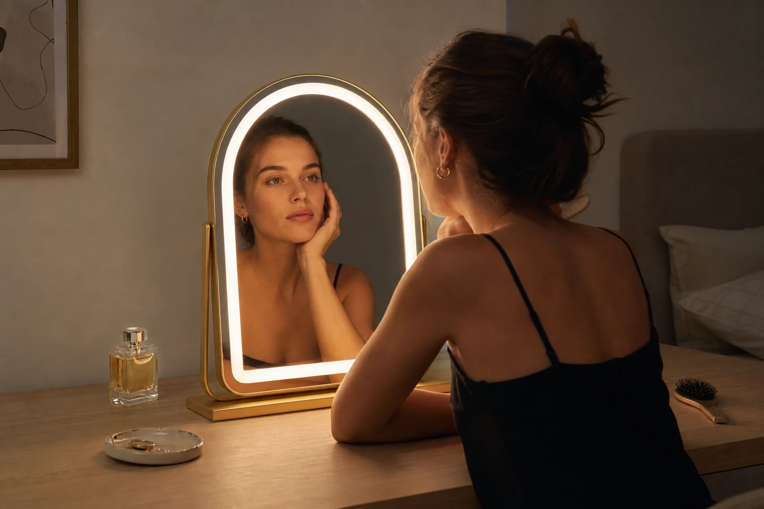 Woman at a lit arched vanity mirror